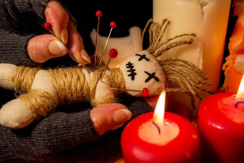 Voodoo binding doll wrapped in thread beside red candles